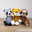 Load image into Gallery viewer, Crocheted raccoon, tiger, and sloth toys sitting on wood.