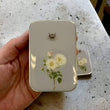 Load image into Gallery viewer, Notions Tin by Firefly Notes featuring vintage rose and bee design held in a hand on a textured surface.
