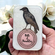 Load image into Gallery viewer, Notions Tin Firefly Notes featuring a crow design and the words Bits &amp; Baubles on a vintage-style tin.
