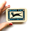 Load image into Gallery viewer, Notions Tin by Firefly Notes featuring black cat illustration and safety match label design
