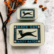 Load image into Gallery viewer, Notions Tin by Firefly Notes featuring a vintage black cat illustration on a safety matchbox design.
