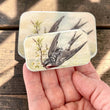Load image into Gallery viewer, Notions Tin by Firefly Notes featuring a swallow in flight and cherry blossoms, symbolizing spring renewal.
