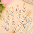 Load image into Gallery viewer, Numbered Stitch Markers for knitting and crochet with numbers 0-9 and rose gold clasps on a soft background.
